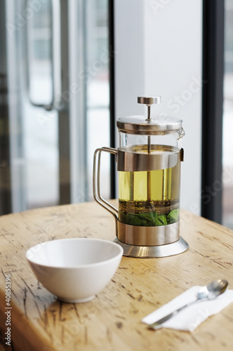 French-press with green tea and cup on the wooden table