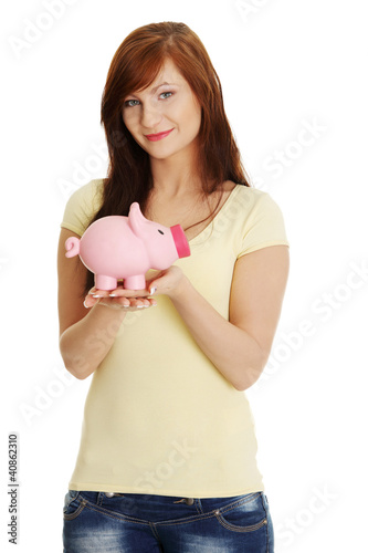 Young woman with her piggy bank, isolated on white background  © Piotr Marcinski