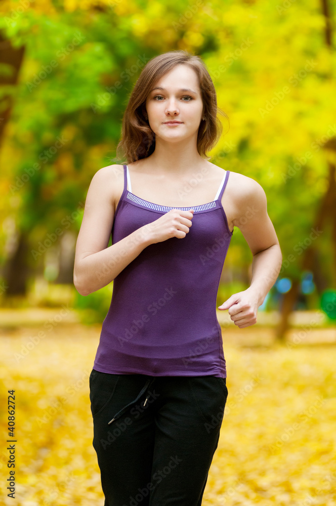 A young girl running in autumn park A young girl running in autumn park