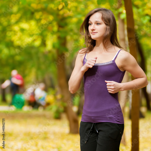 Fototapeta Naklejka Na Ścianę i Meble -  A young girl running in autumn park