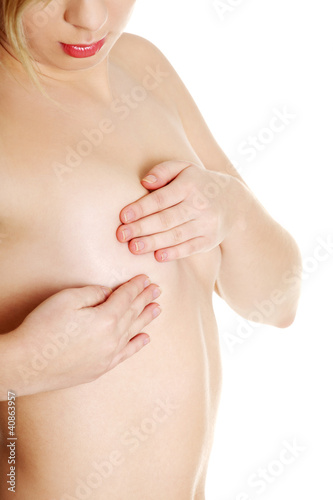 Young Caucasian adult woman examining her breast for lumps or si