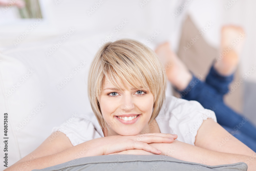 lächelnde blonde frau liegt auf dem sofa lächelnde blonde frau liegt auf dem sofa