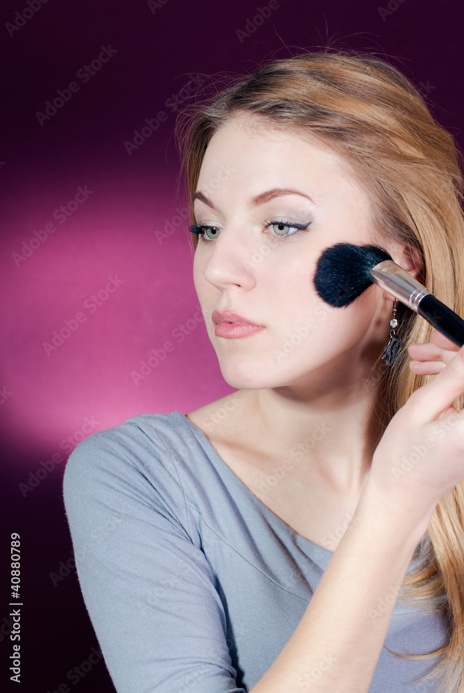 Obraz premium Young blond lady applying blush