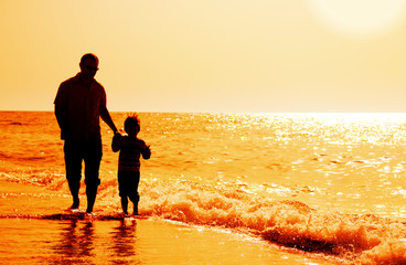 silhouettes of father and son on sunset sea background