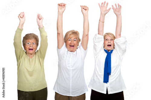 Three senior women raising hands.