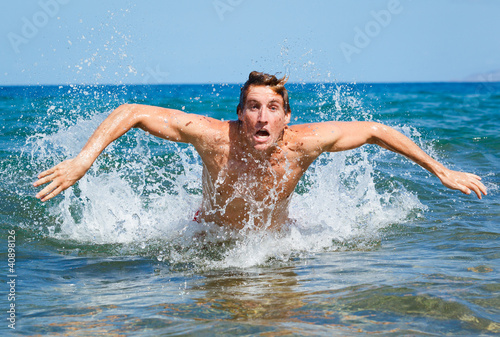 man swimming butterfly strokes in ocean © EpicStockMedia