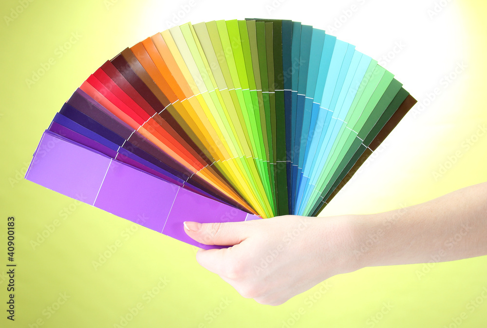 Fototapeta premium hand holding bright palette of colors on green background