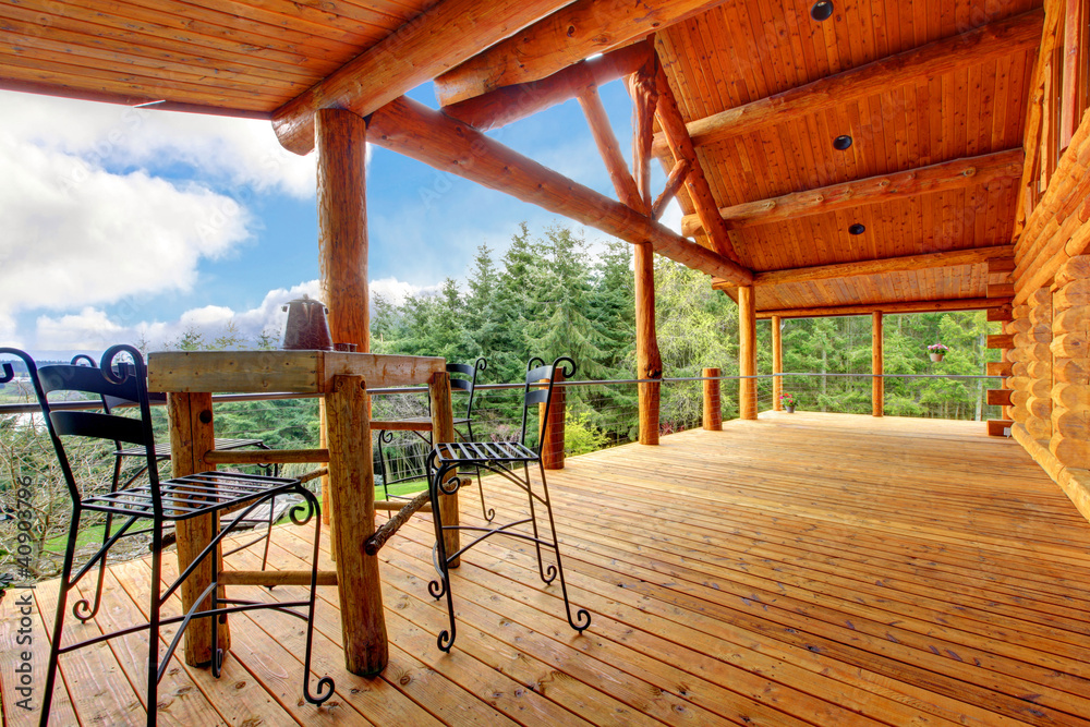 Porch of the log cabin with small table and forest view. Porch of the log cabin with small table and forest view.