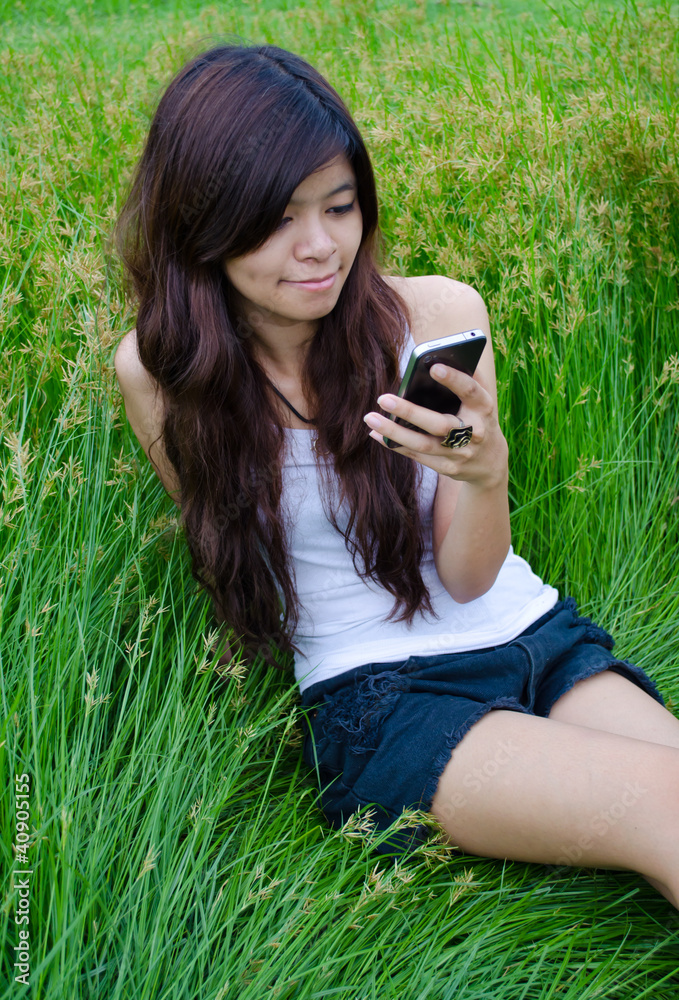asian cute girl texting on meadow asian cute girl texting on meadow
