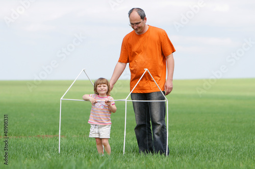 father and chld building toy house on natural background