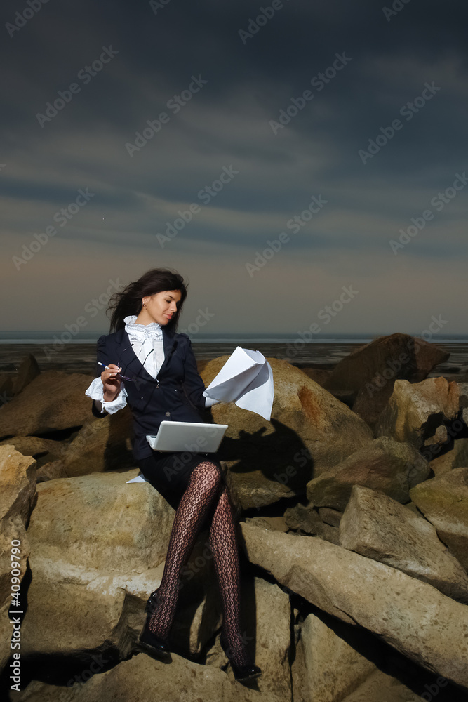 Business lady sitting on the rocks by the sea