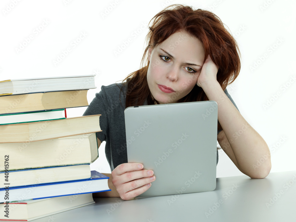 Pupil with touchpad behind pile of books on white background Pupil with touchpad behind pile of books on white background