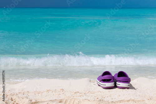 Pair of colored sandals on a white sand beach © Cristian Santinon