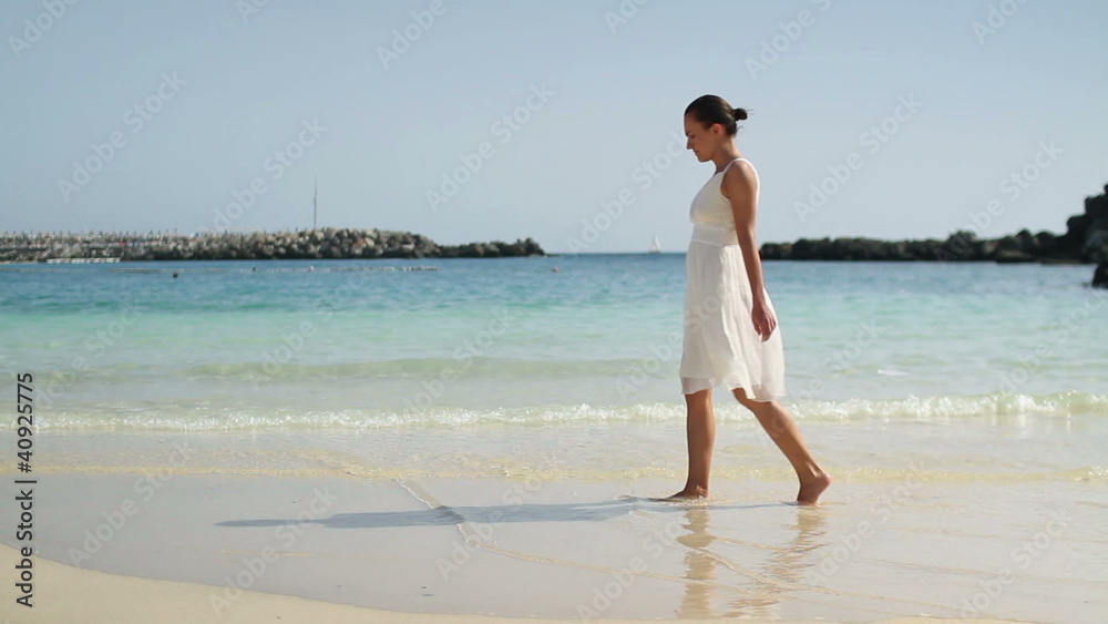 Woman in white dress walking on the beach Woman in white dress walking on the beach