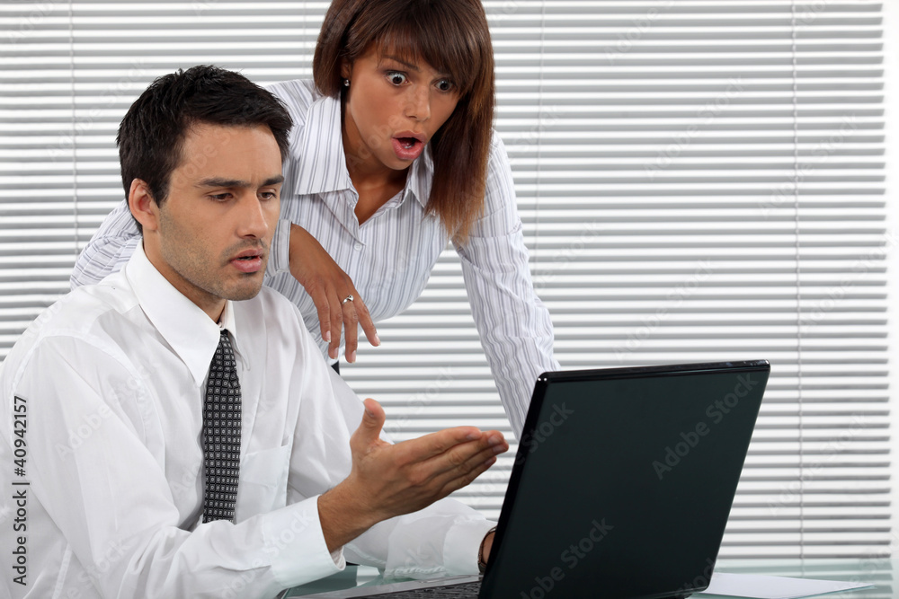 Shocked business couple in front of laptop Shocked business couple in front of laptop