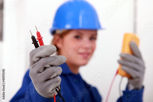 A female electrician holding a voltmeter.