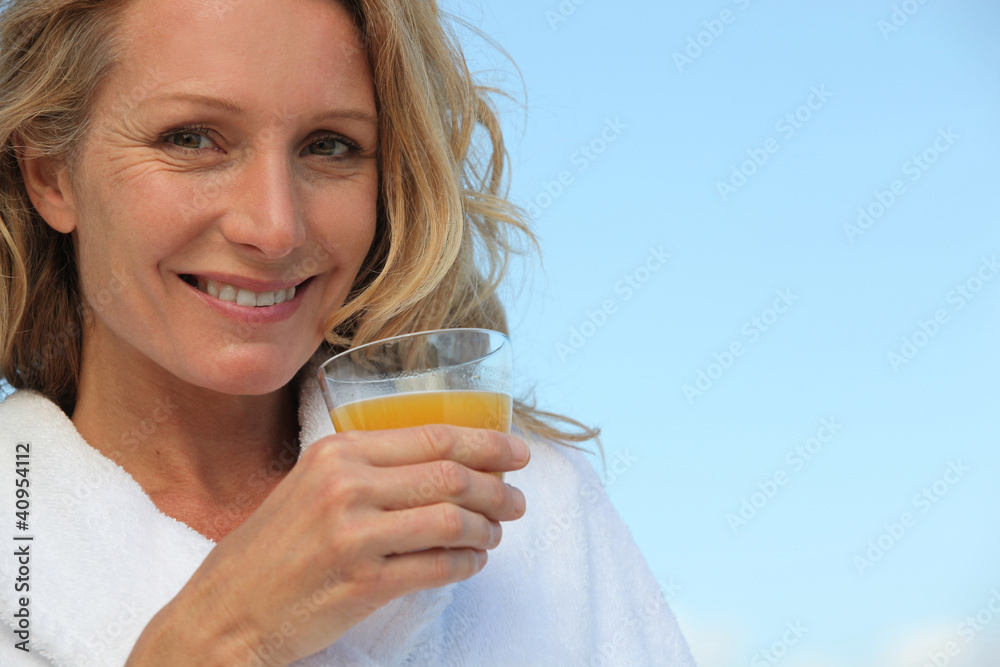 Blond woman outdoors drinking orange juice Blond woman outdoors drinking orange juice