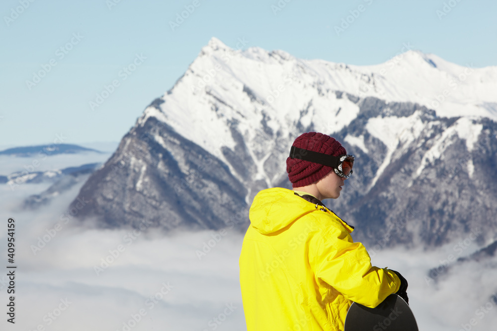 Teenage Snowboarder Admiring Mountain View Whilst On Ski Holiday