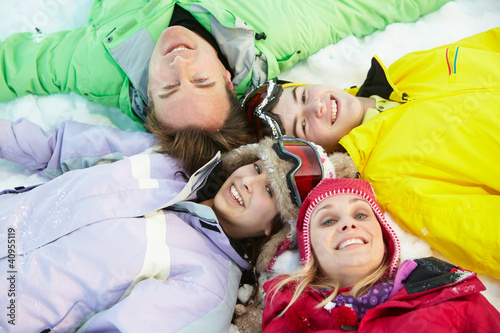 Overhead View Of Teenage Family Lying In Snow On Ski Holiday In