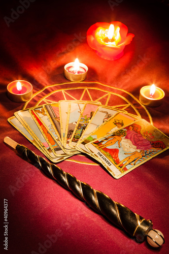 Tarot cards with a magic wand illuminated by candlelight.