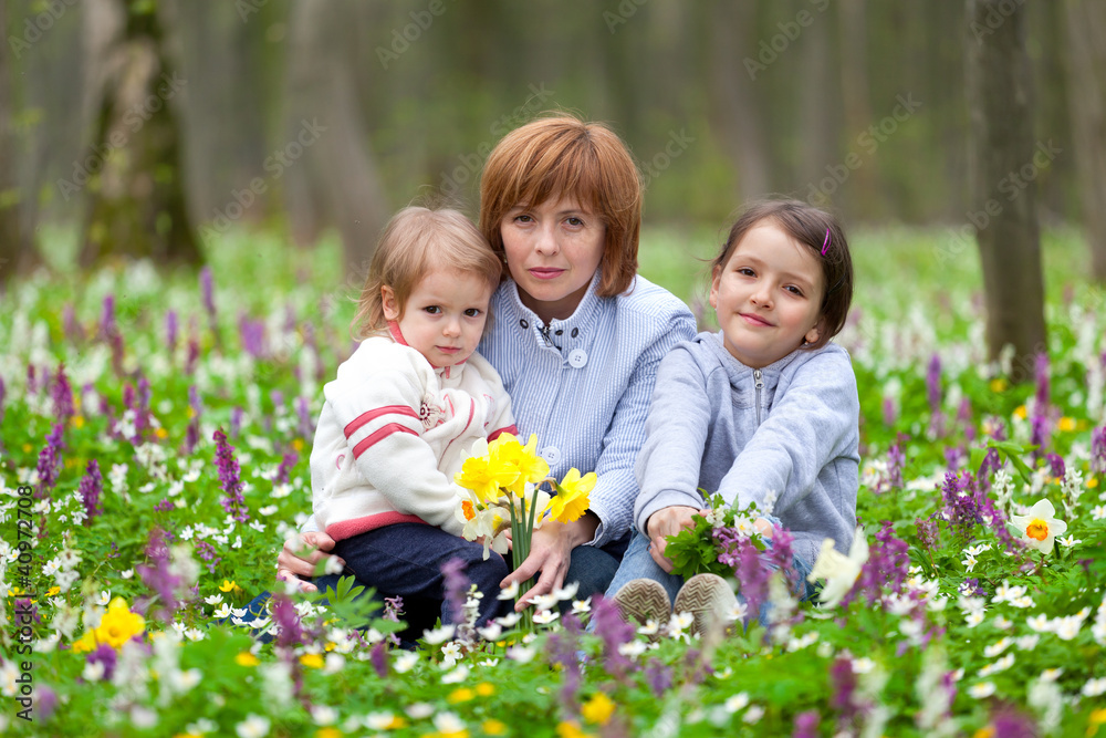 Mother and her two little daughters picking flowers in the sprin Mother and her two little daughters picking flowers in the sprin