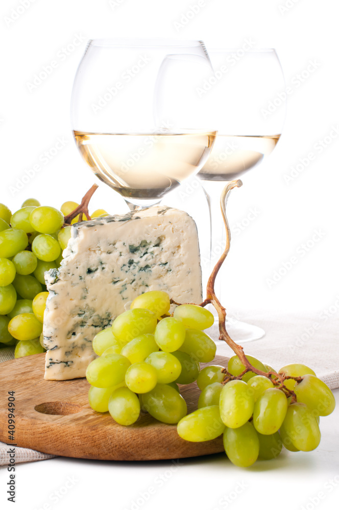 Two glasses of white wine, blue cheese and a grapes Two glasses of white wine, blue cheese and a grapes