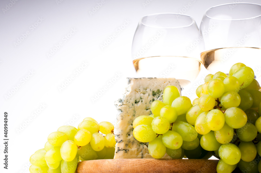 Two glasses of white wine, blue cheese and a grapes Two glasses of white wine, blue cheese and a grapes