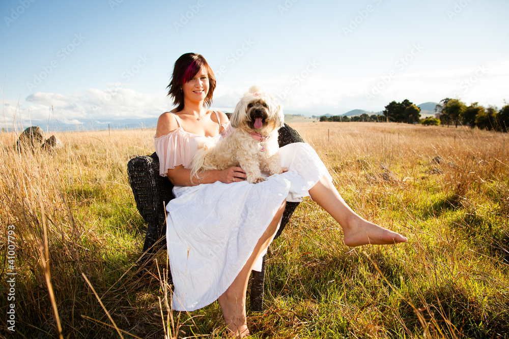 Woman in a field with a poodle on her lap