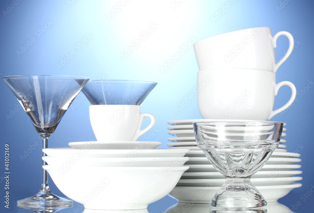 Fototapeta premium empty bowls, plates, cups and glasses on blue background