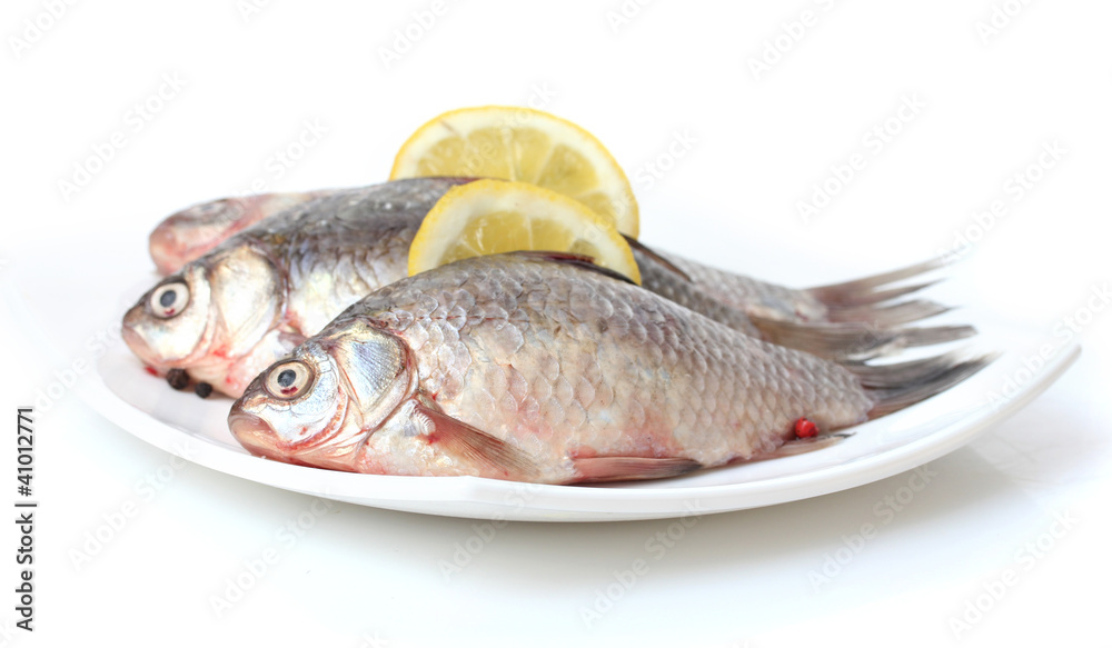 Fresh fishes with lemon on plate isolated on white Fresh fishes with lemon on plate isolated on white