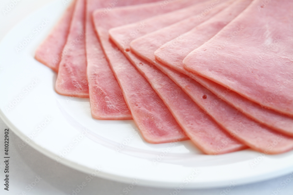 Slices of tasty ham on white dish.