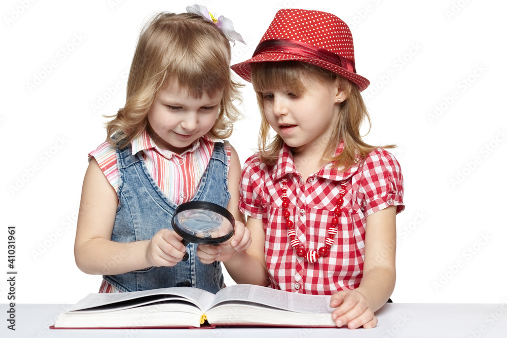 Two little girls reading book through magnifying glass Two little girls reading book through magnifying glass