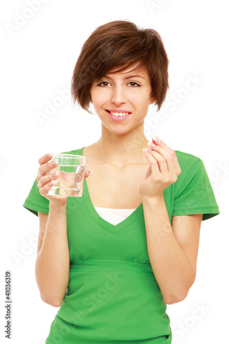 Young woman holding a pill and water, isolated on white