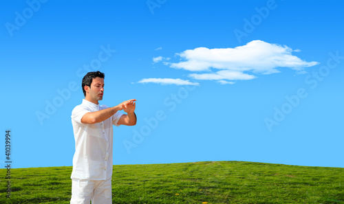 Young man practicing Tai Chi on grassy hill