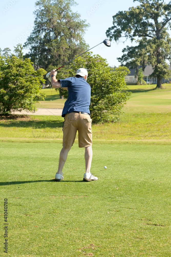 Male golfer teeing off with driver Male golfer teeing off with driver