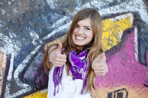 Style teen girl near graffiti wall.