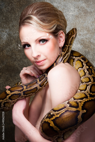 Attractive nude blond woman with python on grey