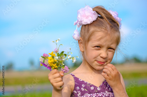 Portrait of a cute child girl with flowers outdoors in sunny day