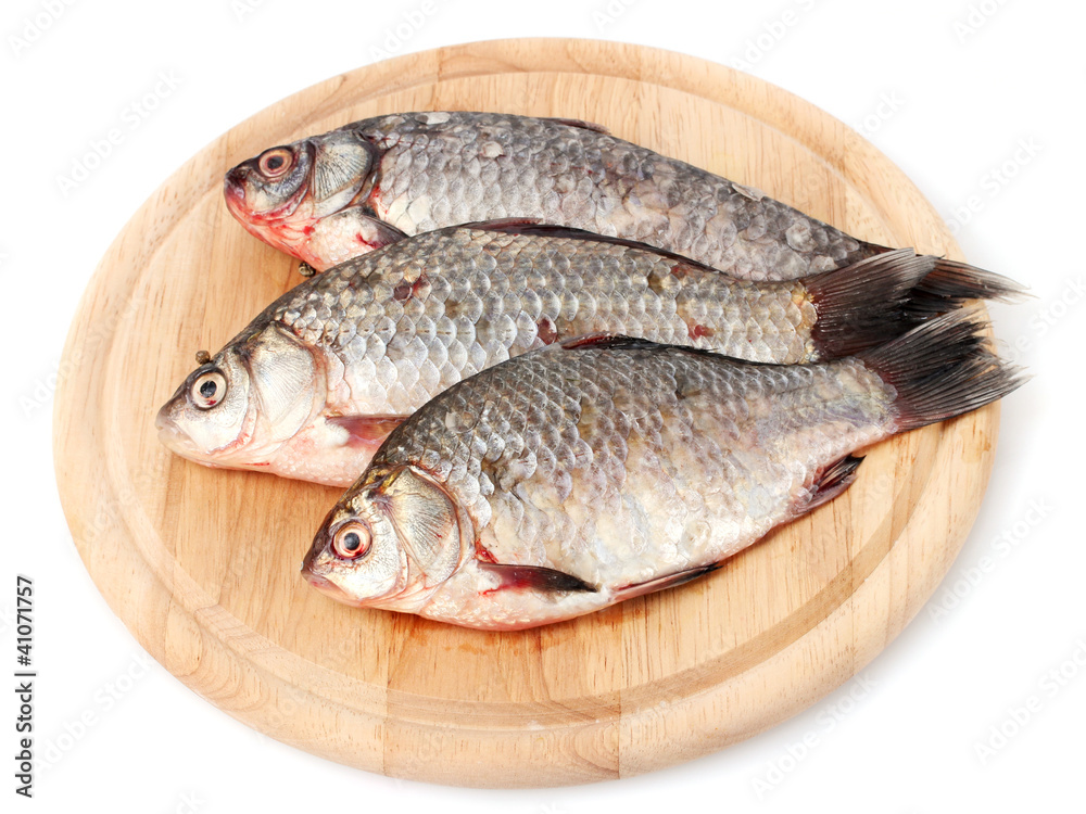 Fresh fishes on wooden cutting board isolated on white Fresh fishes on wooden cutting board isolated on white