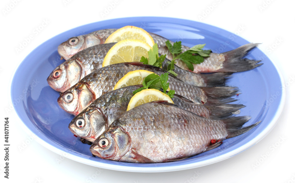 Fresh fishes with lemon and parsley on plate isolated on white Fresh fishes with lemon and parsley on plate isolated on white