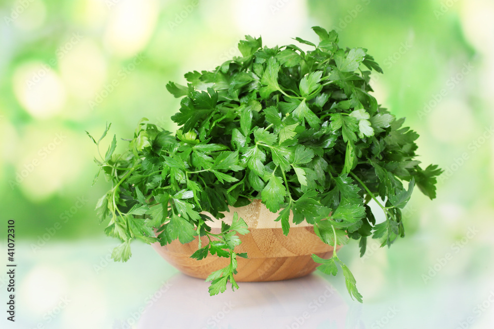 Parsley in a wooden bowl on green background Parsley in a wooden bowl on green background