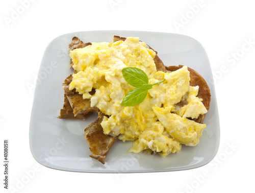 Scrambled Eggs on toasted bagles with  basil on white background
