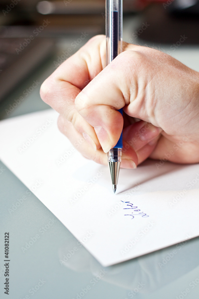 womans hand is writing a letter with a pen womans hand is writing a letter with a pen