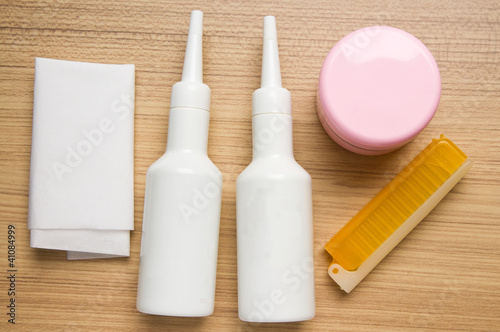 white bottles and comb and pink bottle on wood background
