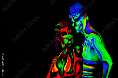 Man and woman with fluorescent bodyart. Black background. Studio photo