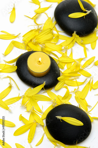 Set of burning yellow candle on stone with yellow flower petals