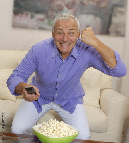 Canvastavla Un señor comiendo palomitas de maíz viendo televisión.