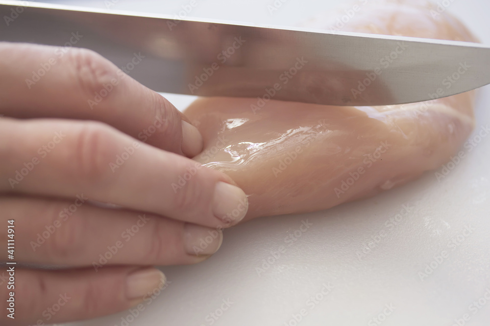 Women Hand sliced fresh chicken breast with a knife. Women Hand sliced fresh chicken breast with a knife.