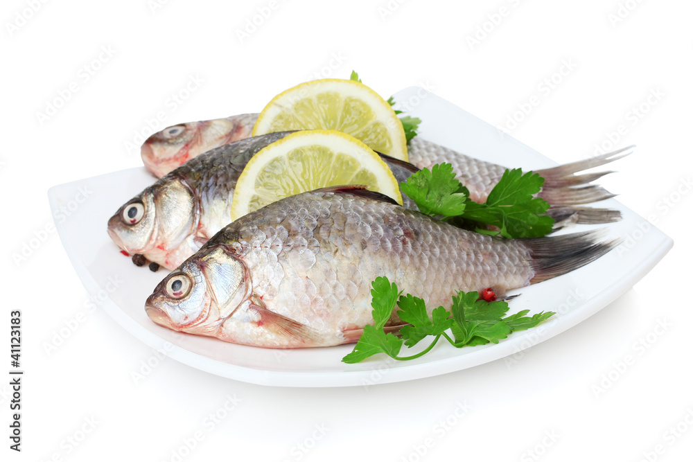 Fresh fishes with lemon and parsley on plate isolated on white Fresh fishes with lemon and parsley on plate isolated on white