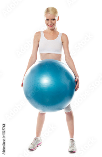 Smiling female athlete holding a big blue ball